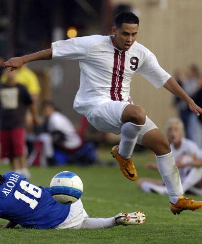 GHS_AHS_DSC0272b Jorge Alvarez (9) of Glencoe hurdles over the tackle attempt by Aloha's Antonio Garcia (16) during second half play.