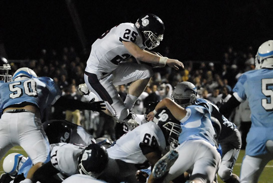 LHS_LOHS_DSC0829b Whit Bissett (25) of Lake Oswego flies over the blocking of teammate Andre Lee (68) to score a one yard touchdown with 1:47 left in the third quarter to put the Lakers up 41-3.