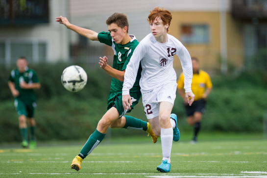 Even McClelland (12) of Milwaukie battle for a ball in midfield against Rex Putnam forward Tanner Ujifusa (8).