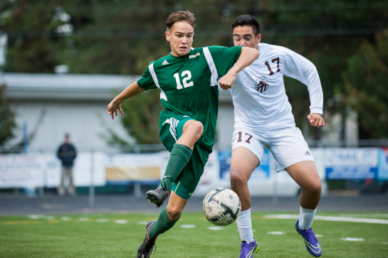 Rex Putnam midfielder Chris Taylor (12) dribbles the ball up the wing under pressure from Jerry Navarrete (17) of Milwaukie.